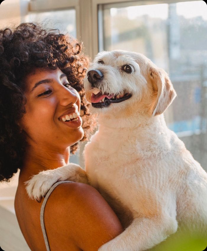 A smiling woman holding a happy white dog